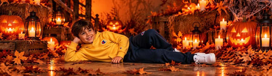 Bambino sdraiato con felpa Champion gialla e pantaloni della tuta blu, in versione Halloween